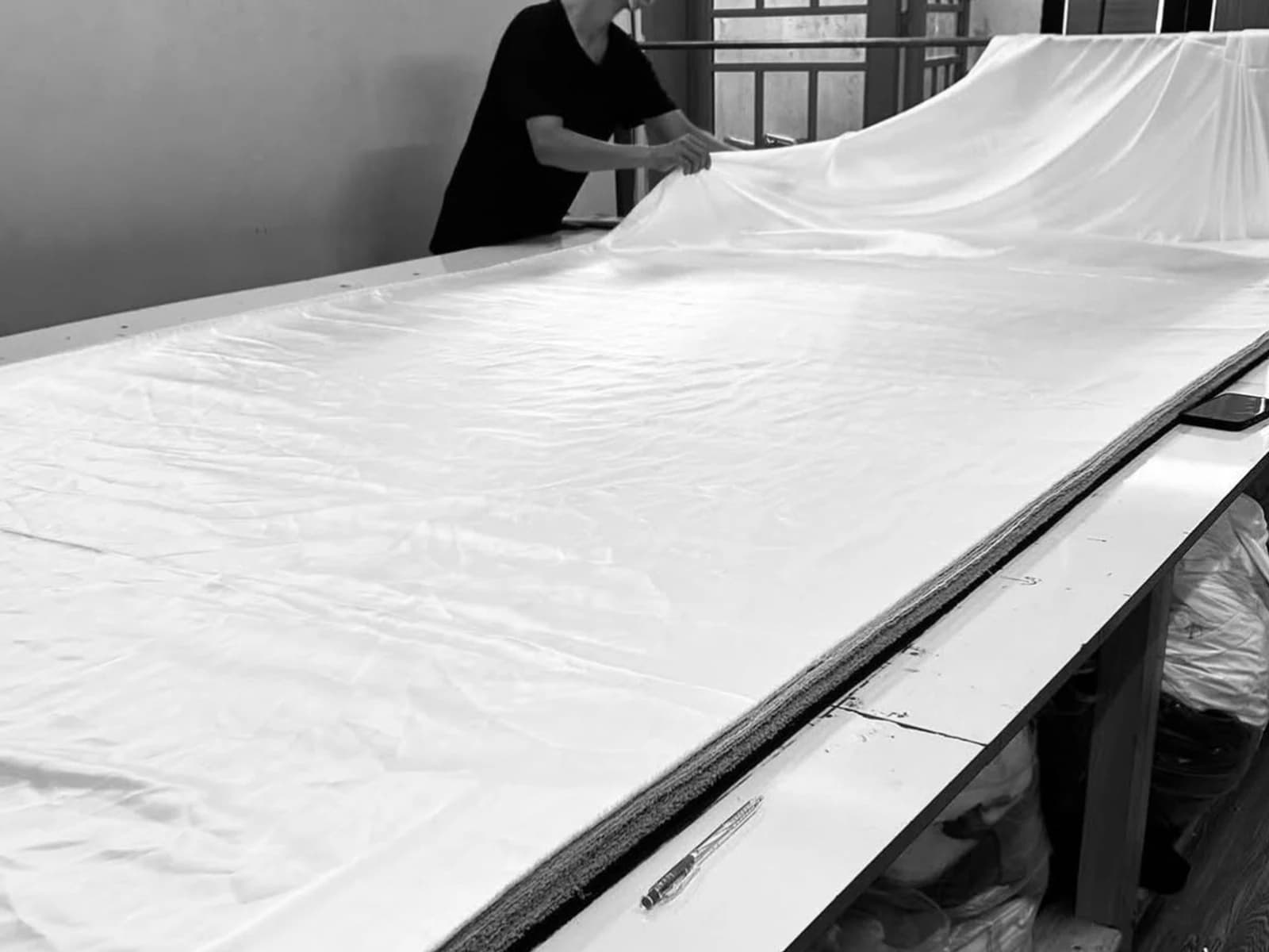Fabric being spread across a long cutting table at a partner workshop