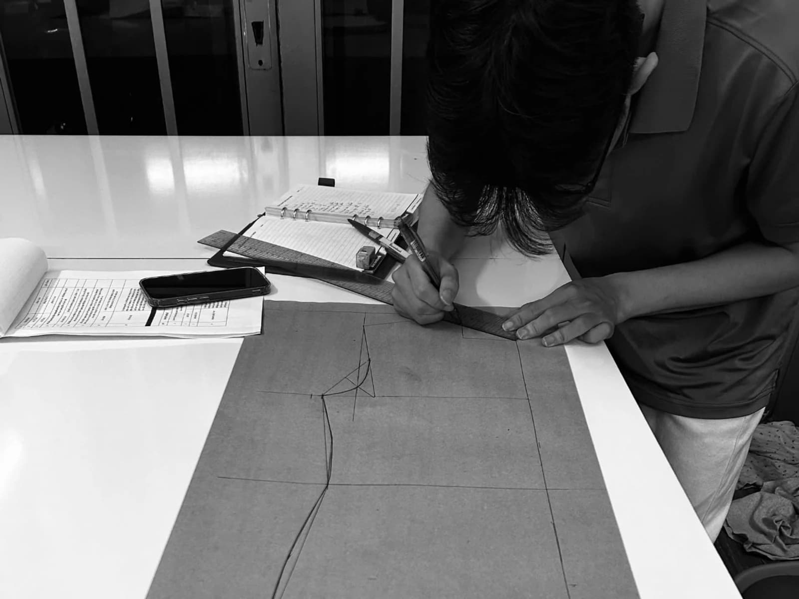 Pattern maker drafting a garment block at a partner workshop table